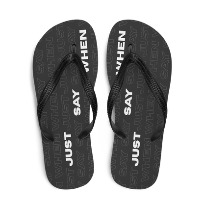 top view of the capital flip-flops in black with bold white ‘just say when’ text and a subtle repeating pattern.