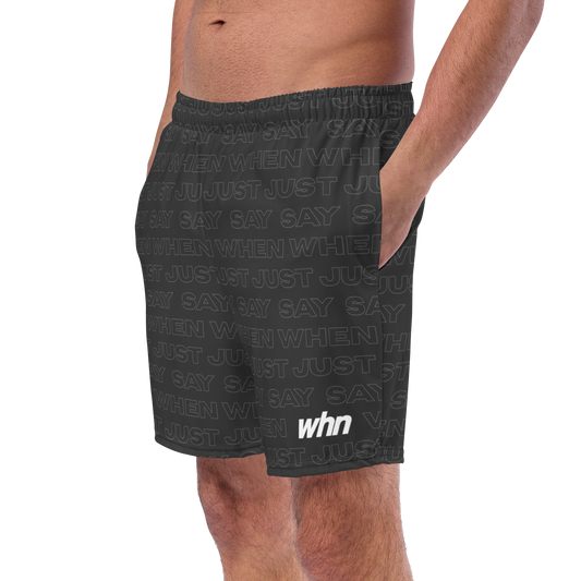 model wearing the capital swim shorts in black featuring an all-over 'just say when' pattern and white whn logo near the hem.